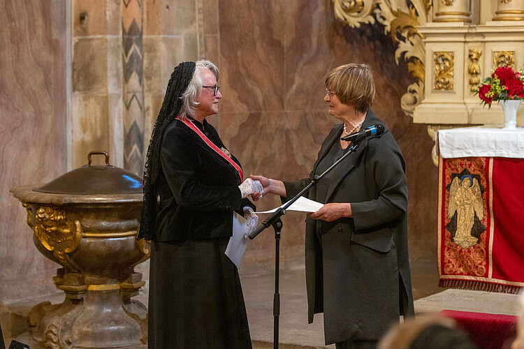 Zwei Frauen stehen sich in einer Kirche gegenüber.