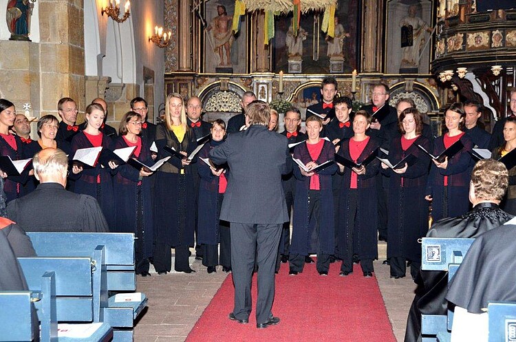 Rund 25 Sängerinnen und Sänger treten als ein Chor während eines Gottesdienstes auf.
