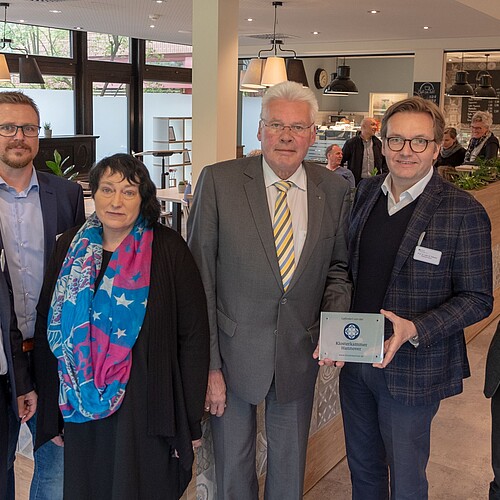 Sechs Personen, darunter Klosterkammer-Präsident Hans-Christian Biallas, stehen vor einem modernden Café in der KRH Psychiatrie Langenhagen.