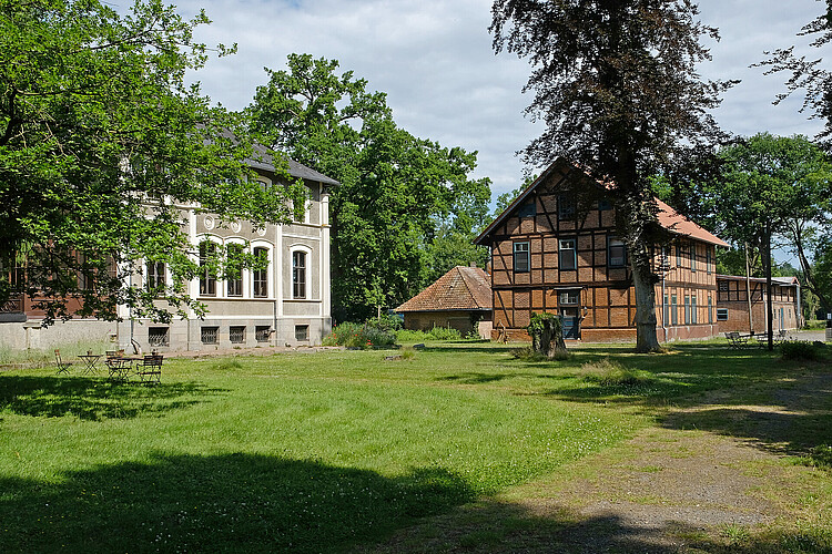 Zu sehen sind zwei historische Gebäude, die zum Klostergut Burgsittensen gehören. Sie sind von einer ebenfalls denkmalgeschützten Parkanlage umgeben.