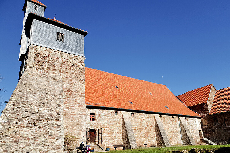Steinerner Kirchenbau mit rotem Dach.
