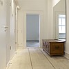 Zwei Türen zu WCs, davor heller Holzboden, eine alte Truhe und ein Spiegel.