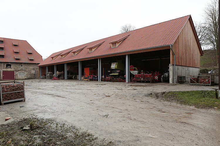 Eine neu gebaute Maschinenhalle grenzt an ein landwirtschaftliches Gebäude.