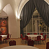 Runde große Tische mit roten Stühlen stehen in einem Raum mit einer weißen Gewölbedecke.
