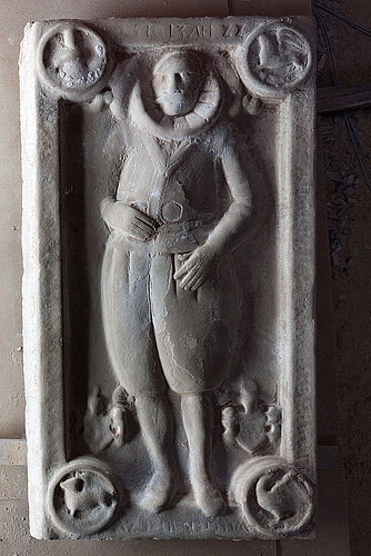 Eine rechteckige Steinplatte, auf der das Bild einer Person als Relief dargestellt ist.