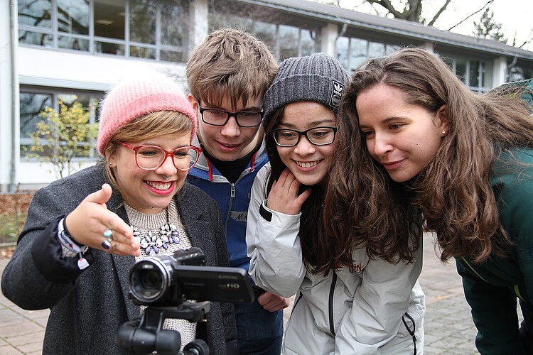 Ein Filmworkshop innerhalb des inklusiven Projektes "ganz schön anders": Drei Mödchen udn ein Junge stehen um eine kleine Filmkamera herum.