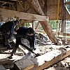 Zwei Personen arbeiten mit Gehörschutz innerhalb der Scheune.