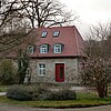 Ein Gebäude aus Stein mit roter Eingangstür auf dem Gelände des Klosters Barsinghausen.