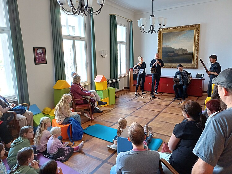 Vier Orchestermusiker spielen vor Publikum.