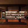 Eine große gläserne Vitrine steht in einem Museumsraum. Einzelne Objekte darin sind beleuchtet.