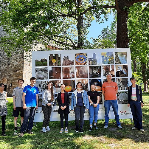 Eröffnung einer Foto-Ausstellung vor der Stiftskirche Wunstorf. Vor einer großformatigen Fototafel stehen Christina Nur, Uwe Stelter, Sabine Löser sowie Schülerinnen und Schüler Evangelischen IGS Wunstorf.