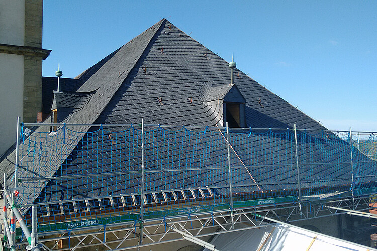 Die neu mit Schieferplatten eingedeckte Dachseite ist noch eingerüstet.
