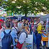 Menschen stehen vor einem Stand in der Innenstadt an
