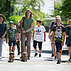 Eine Gruppe von Schulkindern läuft von einer Försterin und einem Förster der Klosterforsten auf einer Straße in ein Waldstück.