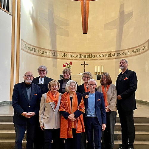 Neun Personen stehen vor dem Altar in einer Kirche.