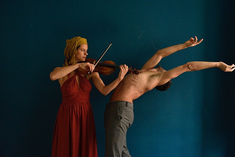 Eine Frau spielt Geige, ein Mann bewegt sich zu den Klängen.