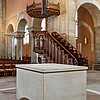 Blick auf einen modernen Altar mit einem Kreuz, das darüber aufgehängt ist, und die Kanzel nach der Instandsetzung.