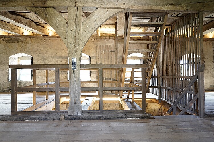 Im Inneren des historischen Schafstalls sind Böden, Treppen und Balken aus Holz.