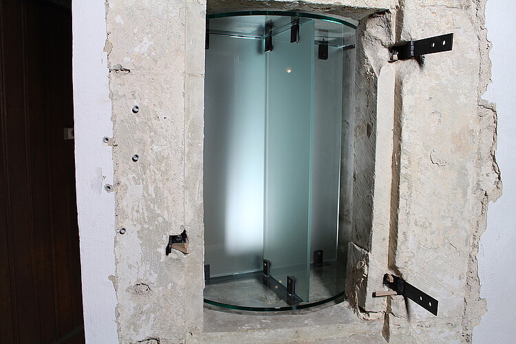 Ein Glaszylinder in einer Wand.