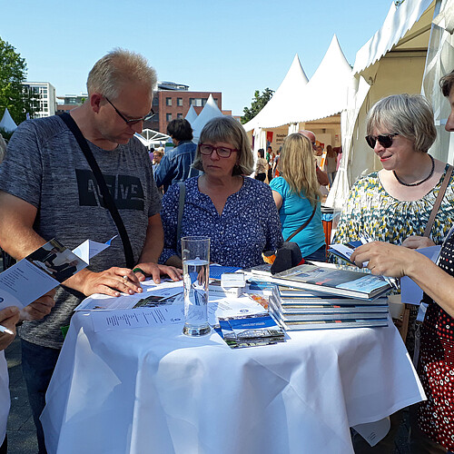Eine Gruppe steht rund um einen Tisch mit Büchern und Flyern zur Klosterkammer Hannover.