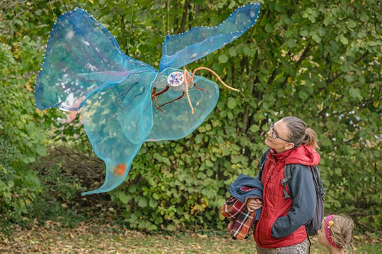 Eine Frau und ein Mädchen schauen sich ein künstlerisch gestaltetes Insekt an.