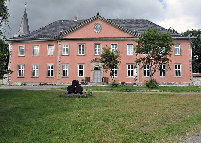 Frontaler Blick auf die Fassade des historischen Gebäudes in einem kräftigen Rot.