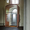 Der Eingangsbereich zu einer Kirche von innen fotografiert. Um die Tür herum ist ein Kasten gebaut, der mit einer Glastür abschließt.