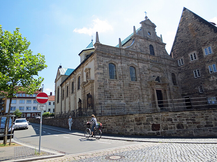 Eine Straße verläuft vor einer steinernen Kirche.