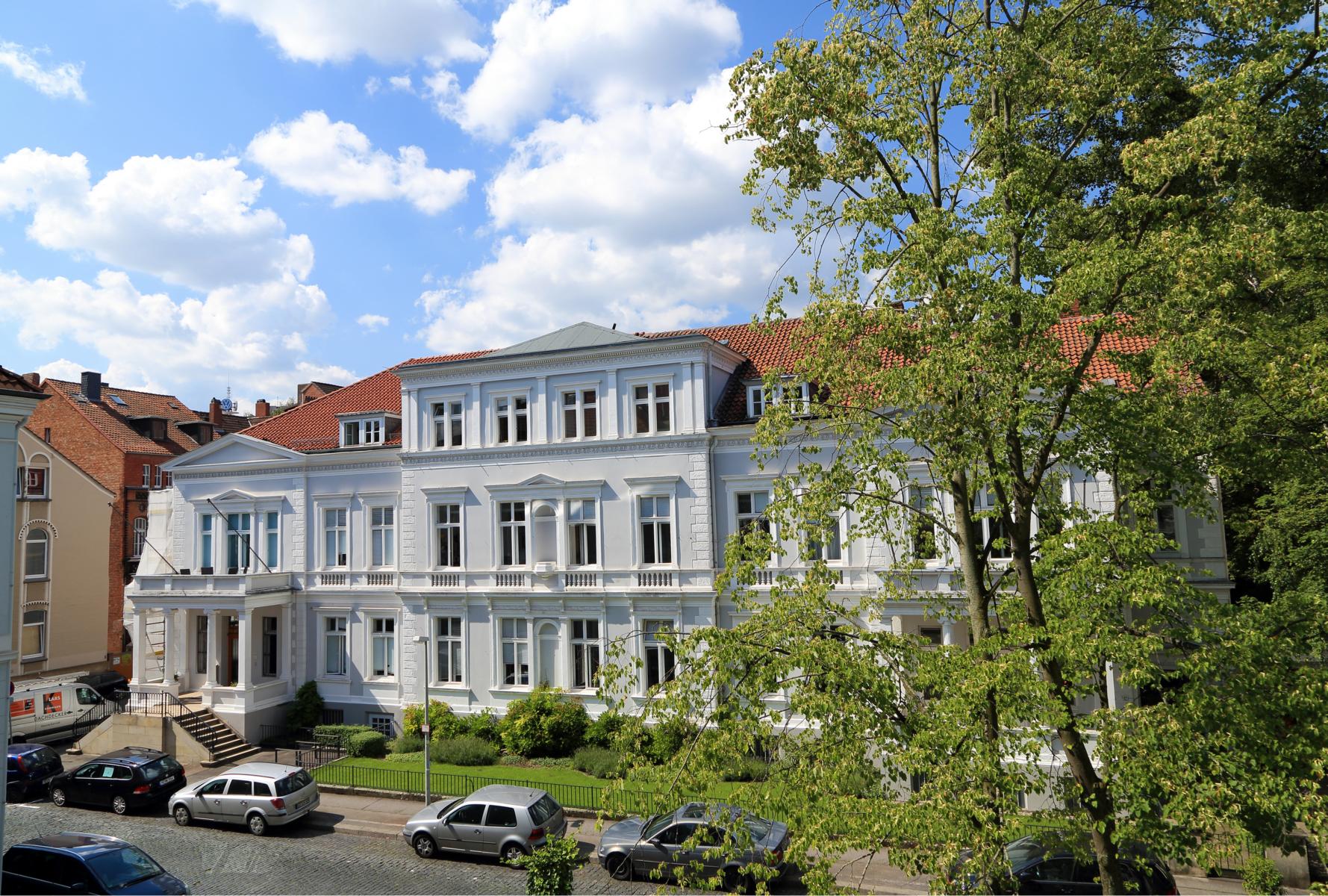Ein großes weißes Gebäude mit Säulen im Eingangsbereich. Ein großes weißes Gebäude mit Säulen im Eingangsbereich.