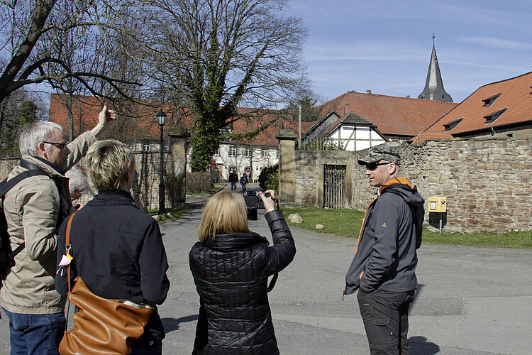 Vier Personen stehen vor der Bruchsteinmauer zum Gelände des ehemaligen Klosters Wöltingerode. Eine Frau macht gerade eine Foto.